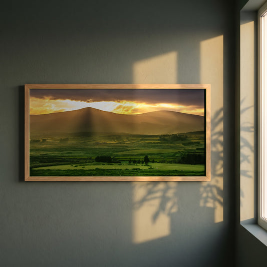 Sugarloaf Mountain, Wicklow framed print in a natural oak frame on a dark green wall beside a window, dappled plant shadow