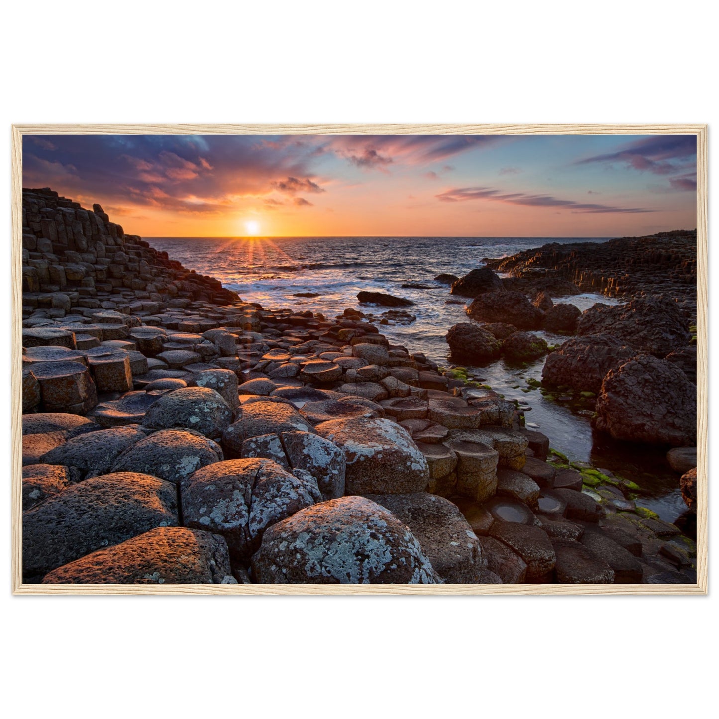 Framed art print of a mesmerizing sunset at Giant's Causeway, featuring iconic basalt columns under a sky painted with warm hues. Captures nature's beauty and tranquility, adding a sophisticated touch to any home or office decor. Ideal for art enthusiasts.