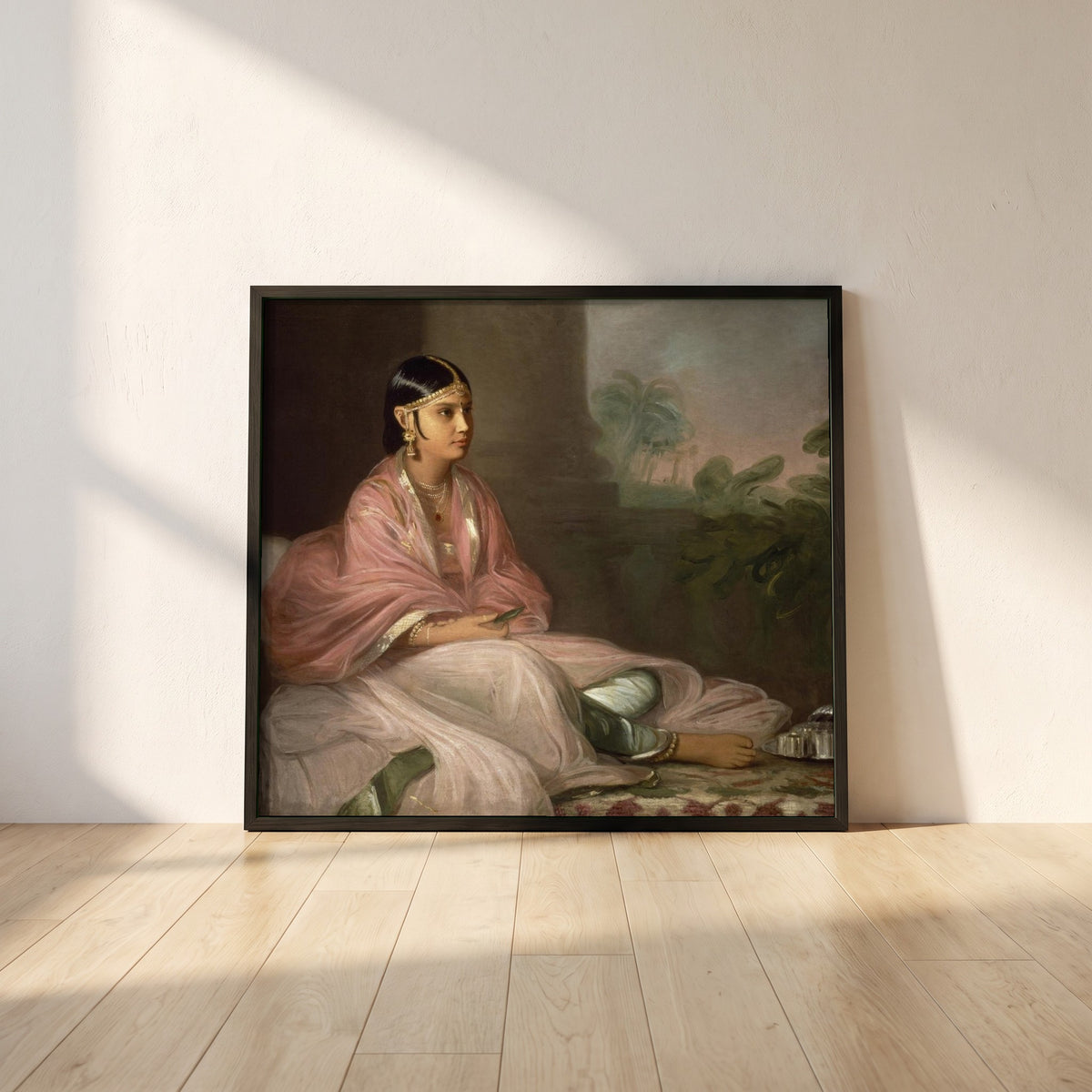 An Indian Lady framed print in a black frame leaning against a white plaster wall on oak floorboards in morning light