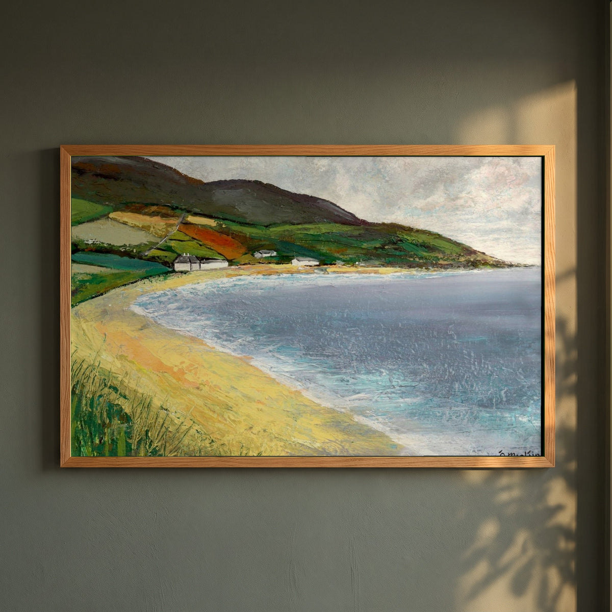 Cushendun Beach, County Antrim framed print in a natural oak frame on a dark green wall beside a window, dappled plant shadow