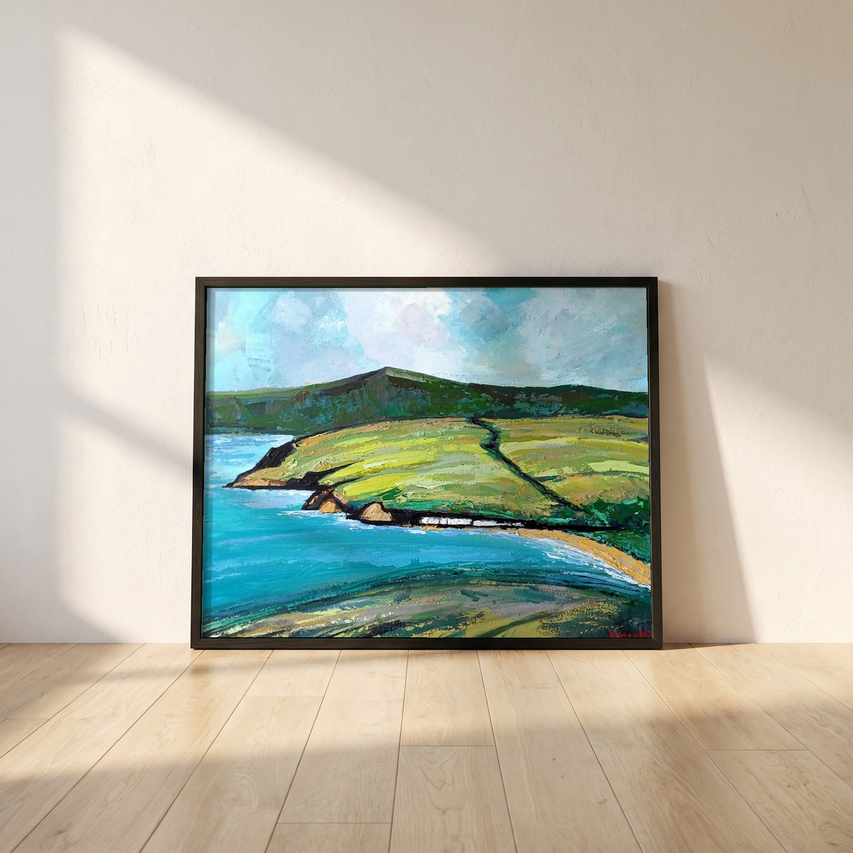 Cushendun framed print in a black frame leaning against a white plaster wall on oak floorboards in morning light