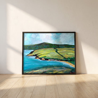 Cushendun framed print in a black frame leaning against a white plaster wall on oak floorboards in morning light