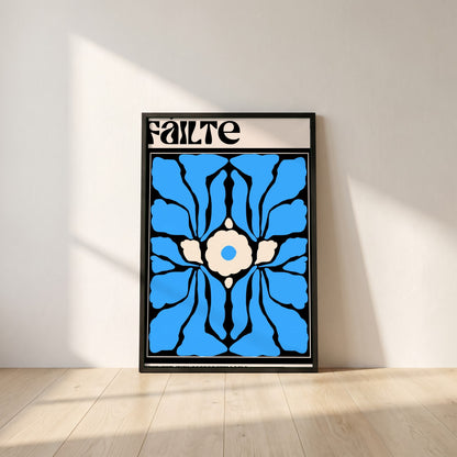 Fáilte framed print in a black frame leaning against a white plaster wall on oak floorboards in morning light