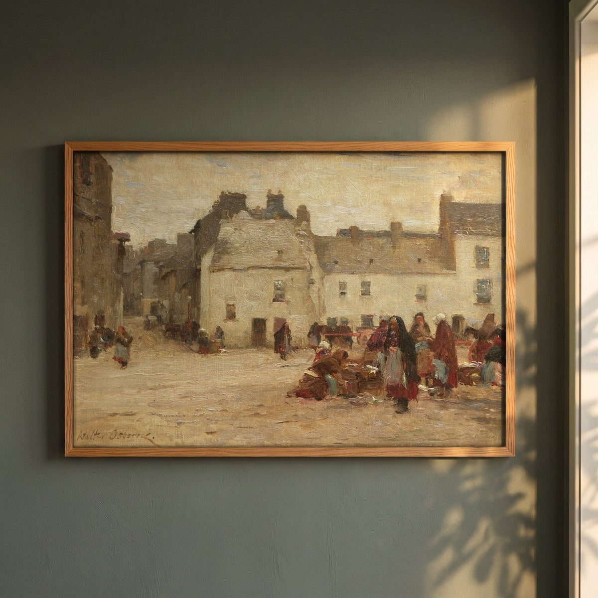 Galway Market Scene by Walter Osborne framed print in a natural oak frame on a dark green wall beside a window, dappled plant shadow