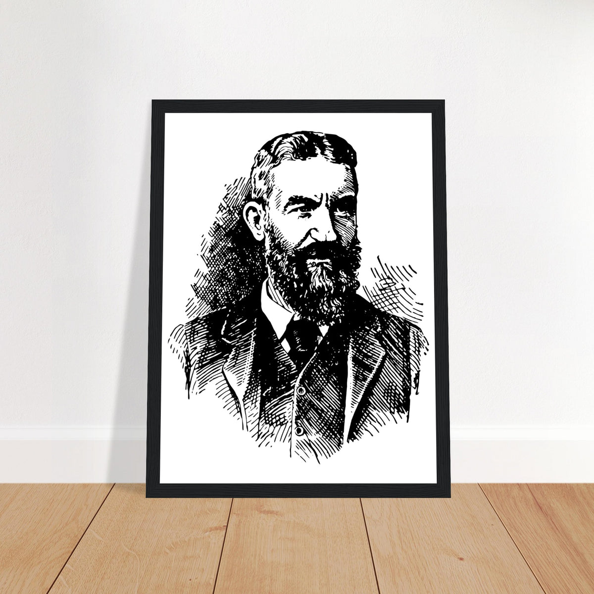 George Bernard Shaw portrait print in a black frame leaning against a white wall on a wooden floor