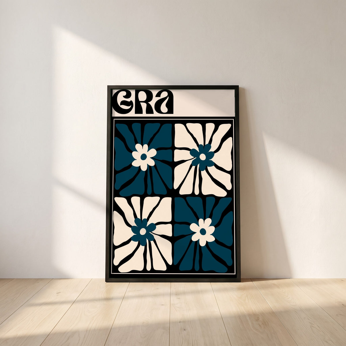 Grá framed print in a black frame leaning against a white plaster wall on oak floorboards in morning light