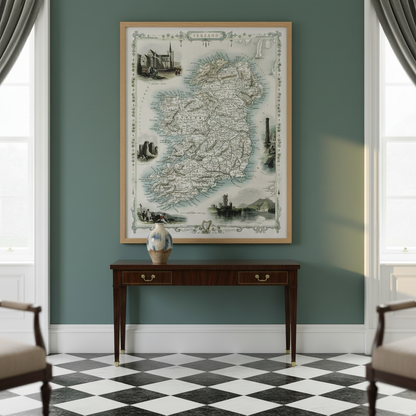 Old map of Ireland in a wood frame above a console with a vase, flanked by armchairs and tall windows