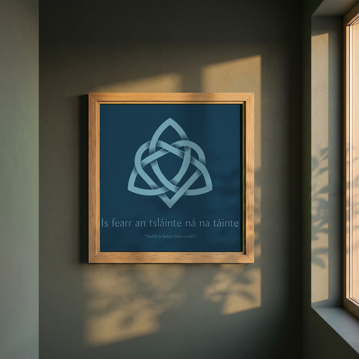 Is fearr an tsláinte ná na táinte framed print in a natural oak frame on a dark green wall beside a window, dappled plant shadow