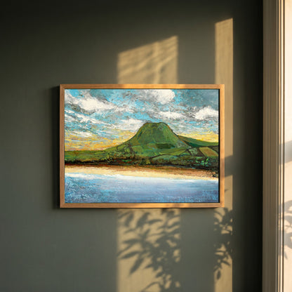 Lurig Mountain at Sunset framed print in a natural oak frame on a dark green wall beside a window, dappled plant shadow