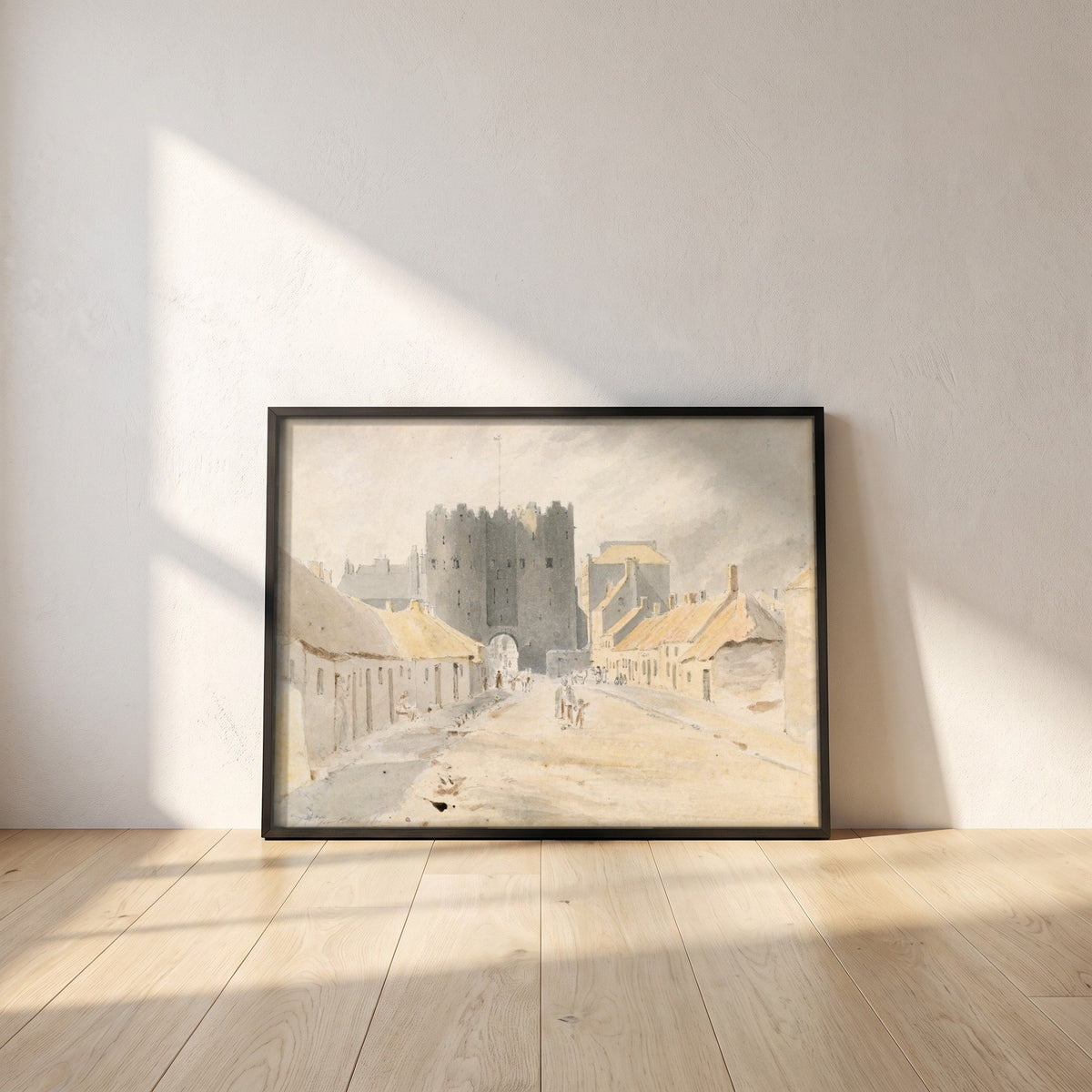 Saint Lawrence's Gate, Drogheda (1819) framed print in a black frame leaning against a white plaster wall on oak floorboards in morning light