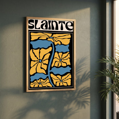 Sláinte framed print in a natural oak frame on a dark green wall beside a window, dappled plant shadow