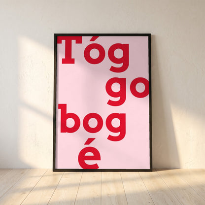 Tóg é go bog é framed print in a black frame leaning against a white plaster wall on oak floorboards in morning light