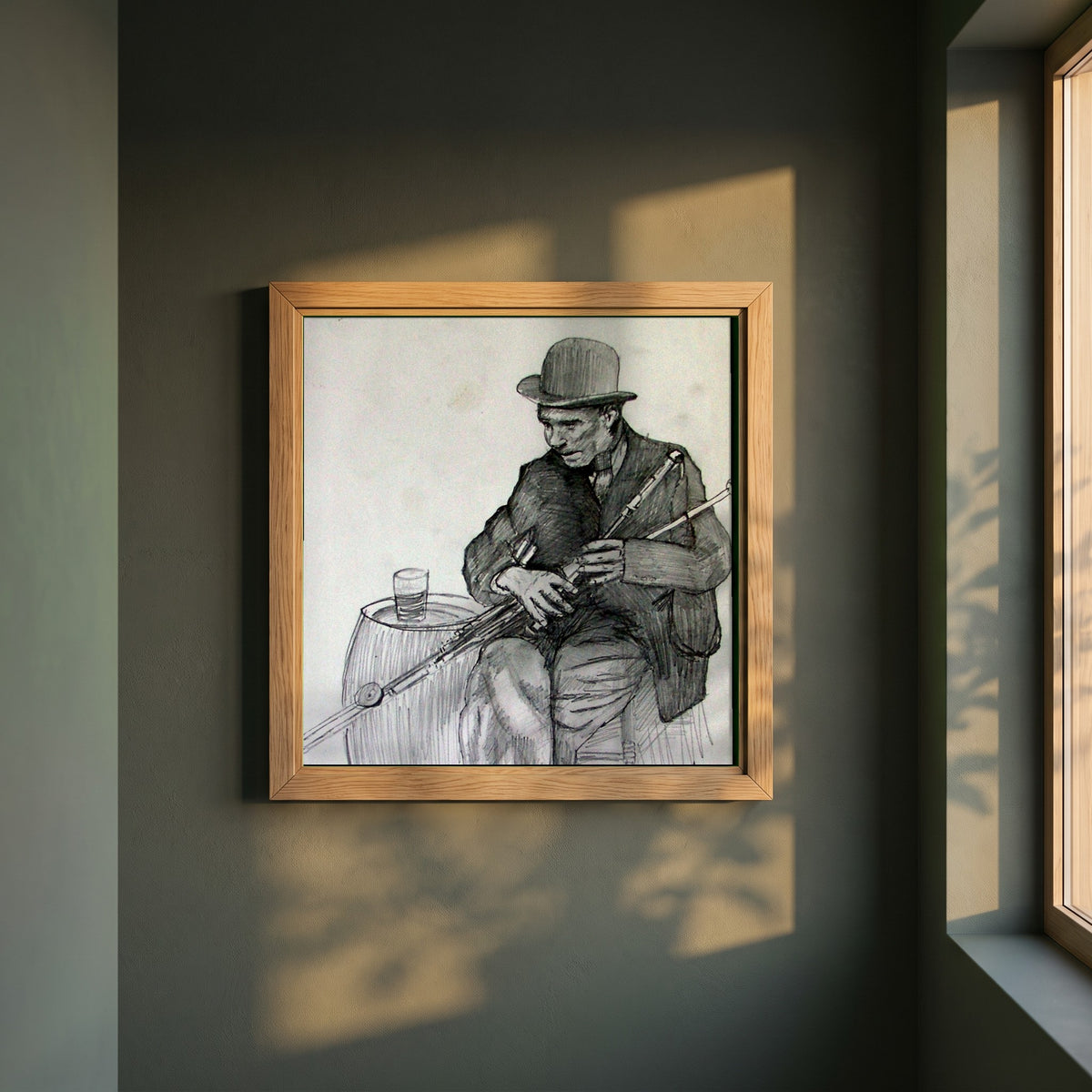 Uilleann Piper framed print in a natural oak frame on a dark green wall beside a window, dappled plant shadow